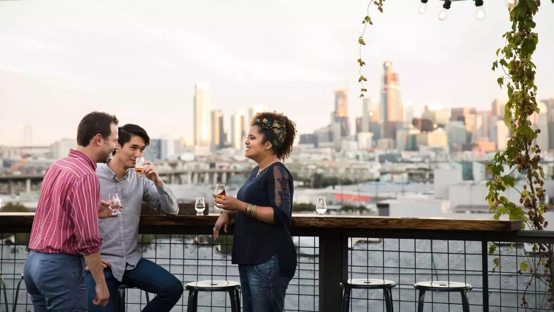 三个人聚集在贝博体彩app安乔蒸馏公司屋顶露台上的一张户外桌子旁, en Californie.