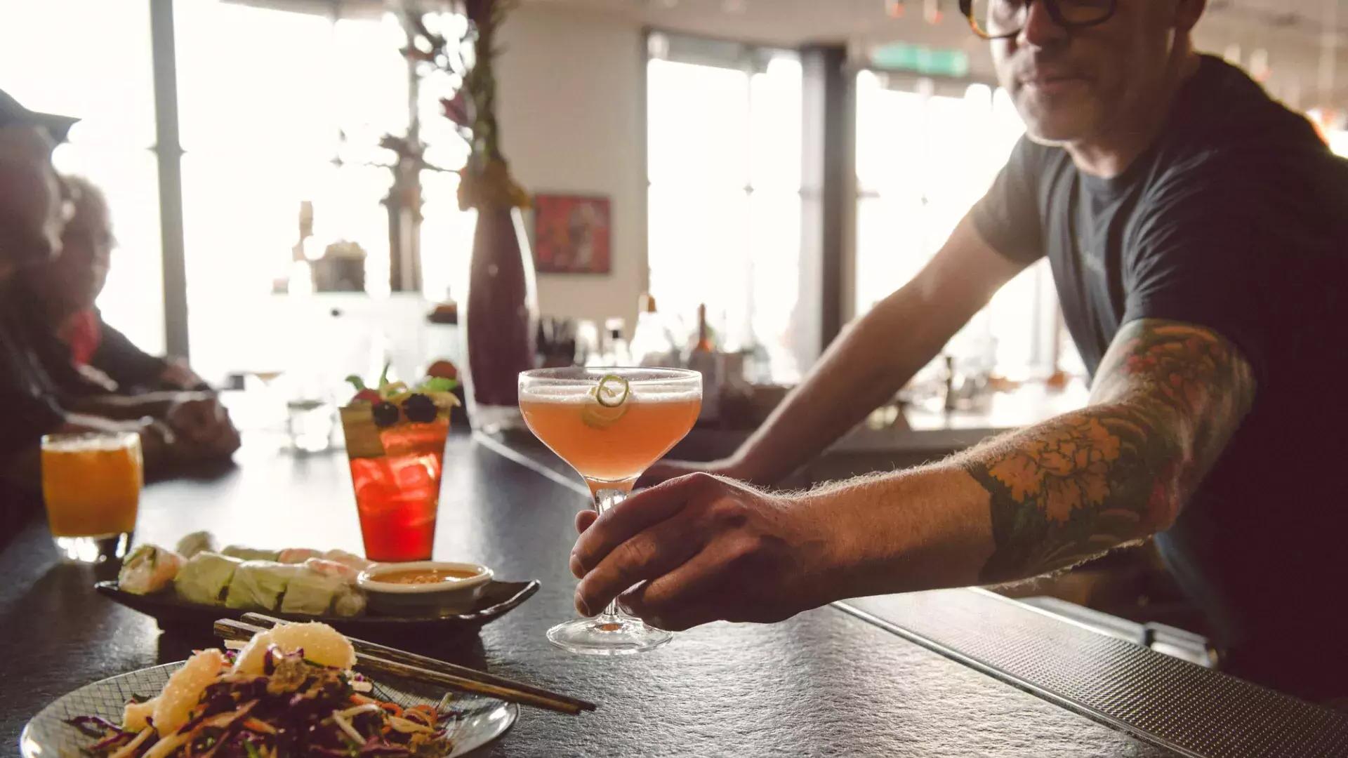 Un barman sert un cocktail à un client dans un bar de San Francisco.